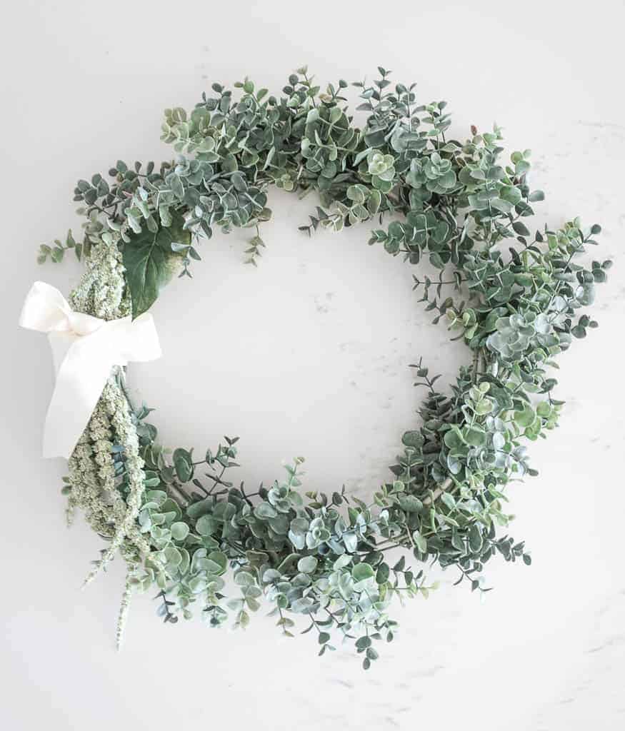 Signed Samantha's instructions on how to make a wreath step by step are included and limited items are needed. Pictured the completed wreath which contains faux green eucalyptus around 5/6ths of the wreath and another long green plant tied with a cream bow on the remaining 1/6th.
