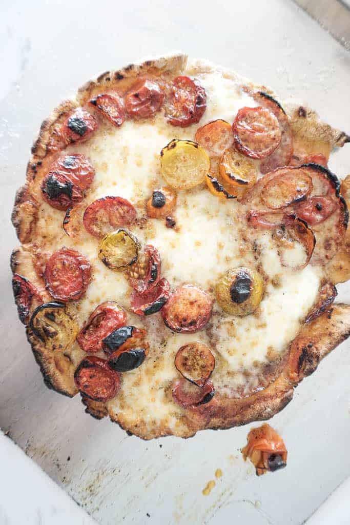 Signed Samantha's recipe for gluten free pizza crust - the cooked crust is pictured with tomatoes on a cheese pizza