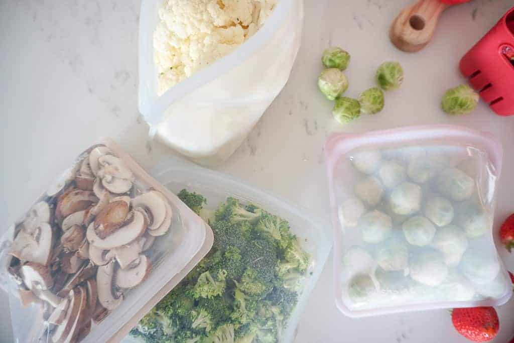 Signed Samantha's fridge organization tips include stasher bags which are pictured here. There are four bags all of which have sliced veggies in them including mushrooms, broccoli, brussel sprouts, and cauliflower