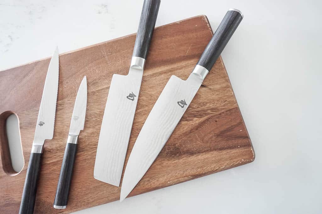 Signed Samantha's splurge worthy kitchen must haves includes sharp knives - four beautiful shun knives are pictured on a cutting board - two large butcher style knives, one pairing knife, and one long serrated knife.