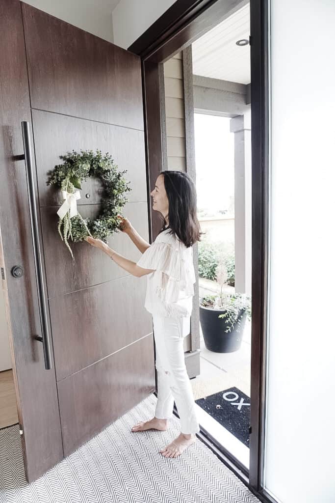 DIY inspiration at Signed Samantha's front door with a DIY eucyalptus wreath that she is hanging.