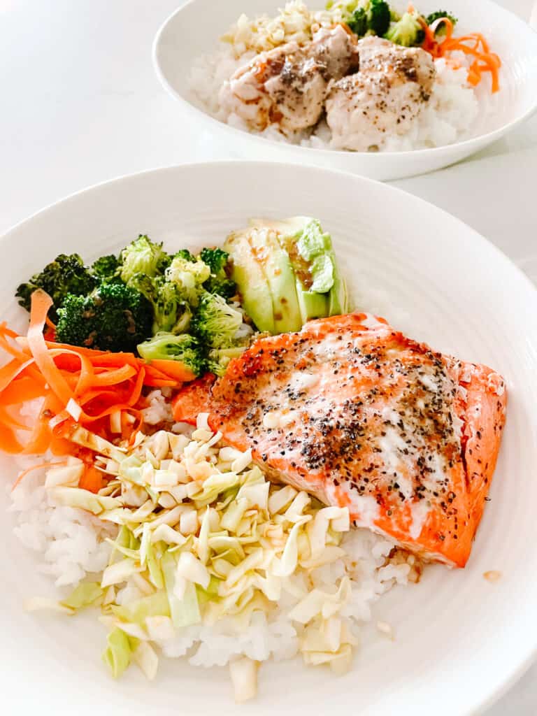 Salmon Rice bowls pictured from a birds eye view with salmon, rice, broccoli, avocado, and shredded carrots.