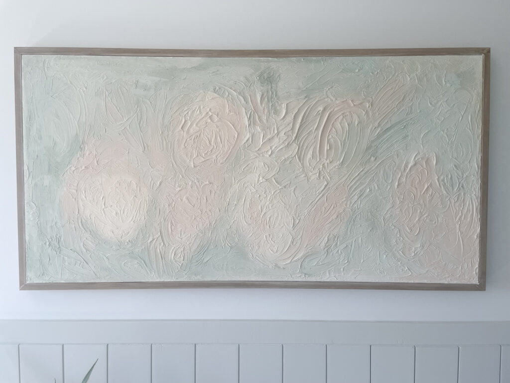 DIY Textured Art hanging on the wall above shiplap. The art contains green and pink colours. Very neutral-like.