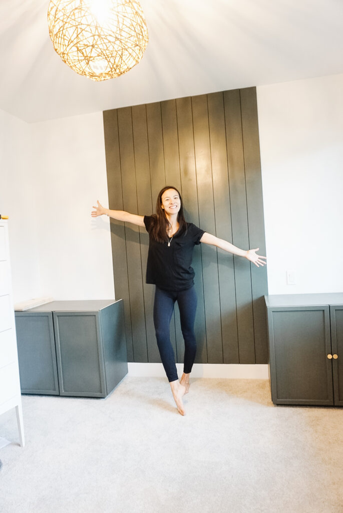 Office reno underway with a cabinet boxes on the ground and signed samantha standing in the middle and shiplap on a portion of the wall