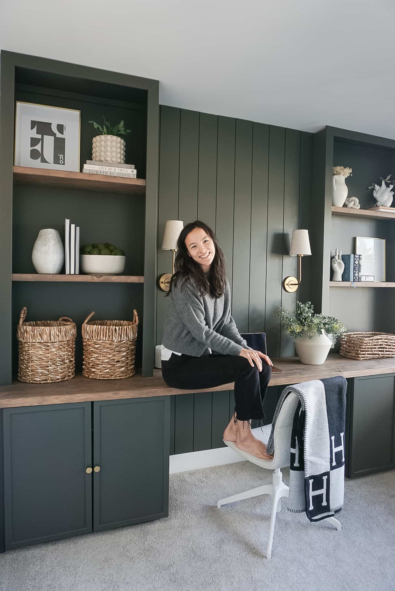 built in home office set up in a deep mossy green with shiplap and lighting at the back, bookshelves on either side and neutral decor throughout. Signed Samantha is sitting on the desk.
