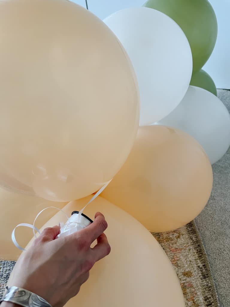 making a DIY balloon garland - tying the ribbon on