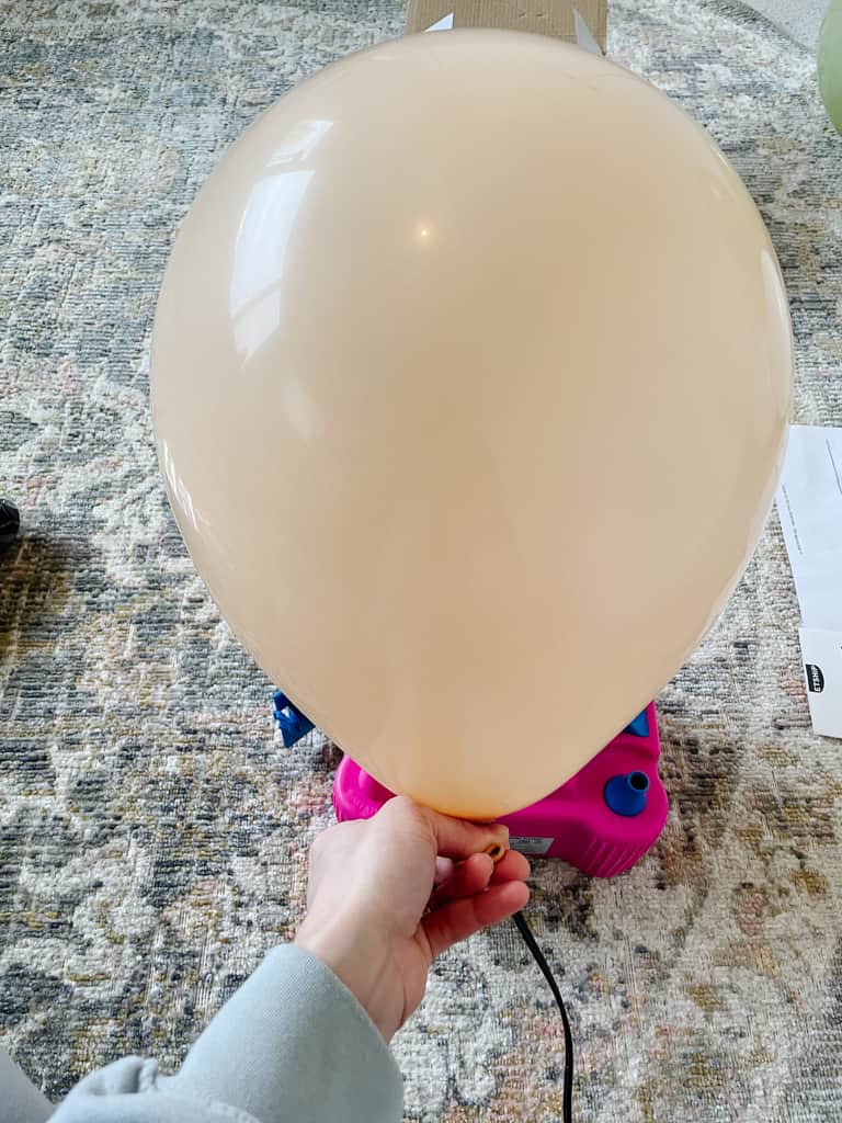 blowing a balloon up to make a balloon garland