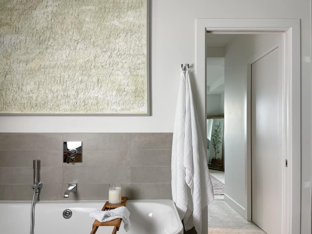 flax home linen towels hanging up next to a bathtub and a piece of art