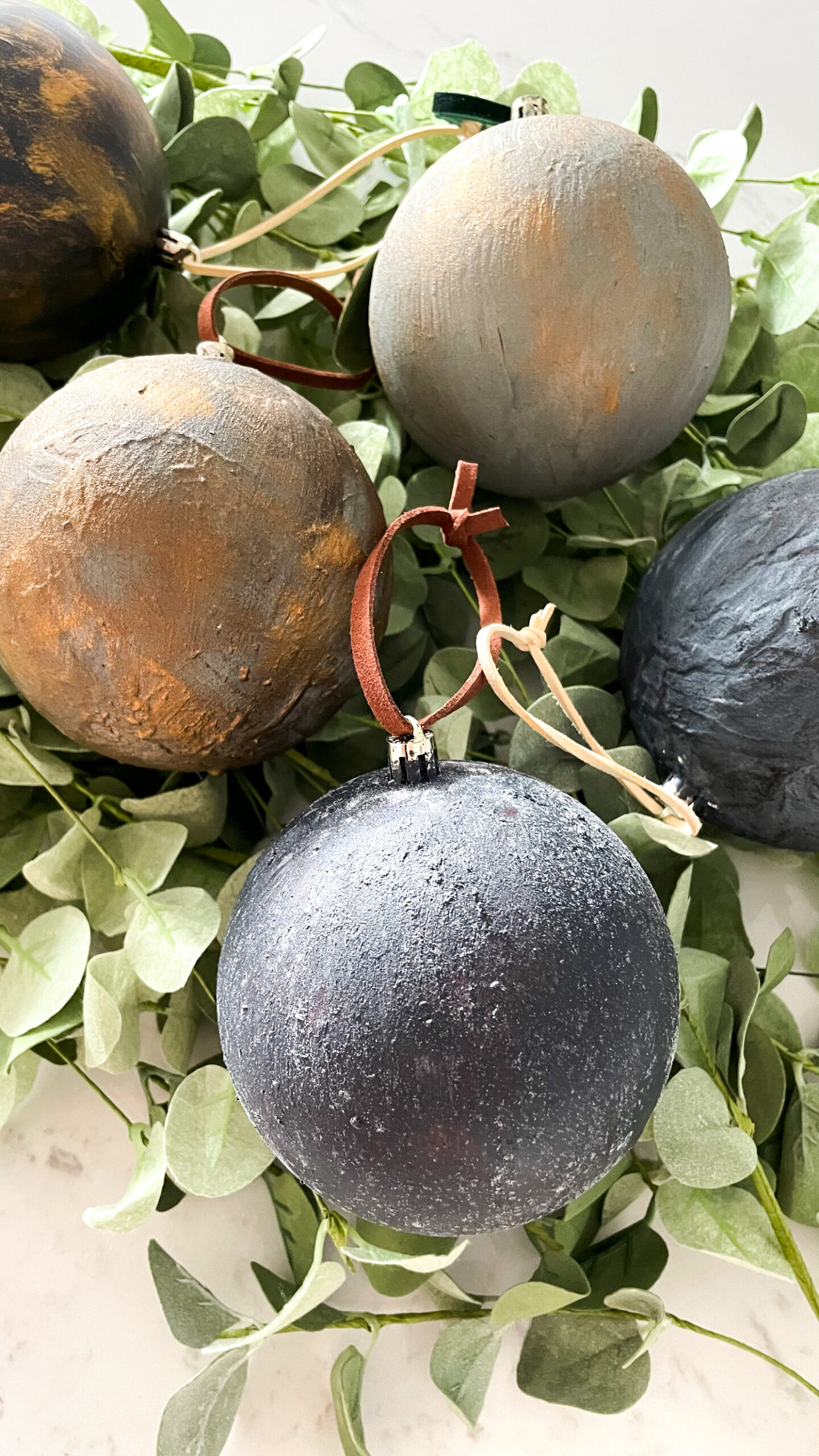 DIY Antiqued Christmas Ornaments on top of eucalyptus