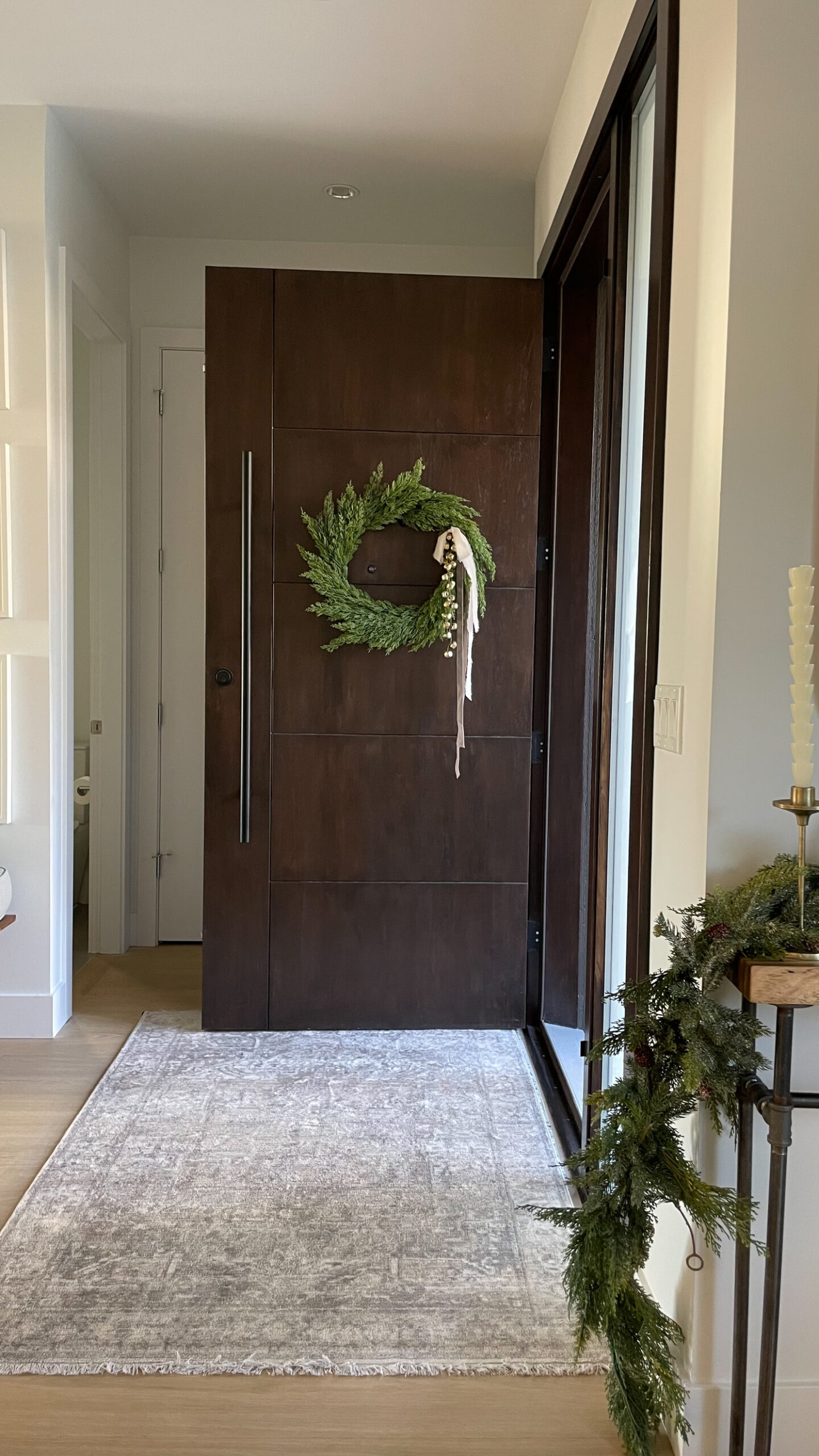 wreath hanging on the front door with ribbon and bells
