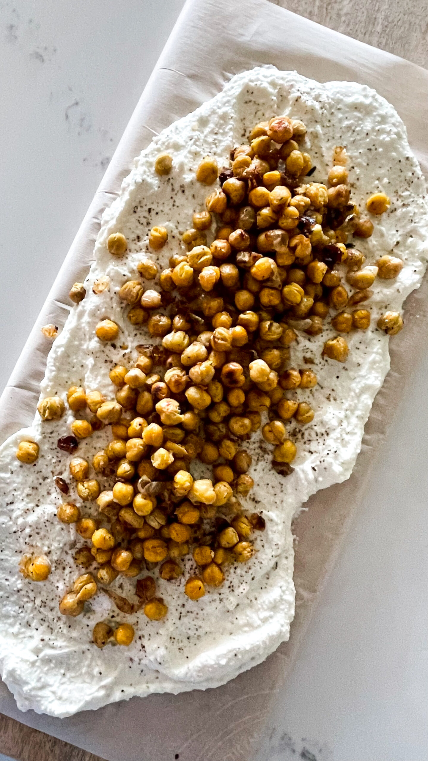 A delicious and simple honey whipped feta on a board with roasted chickpeas overtop