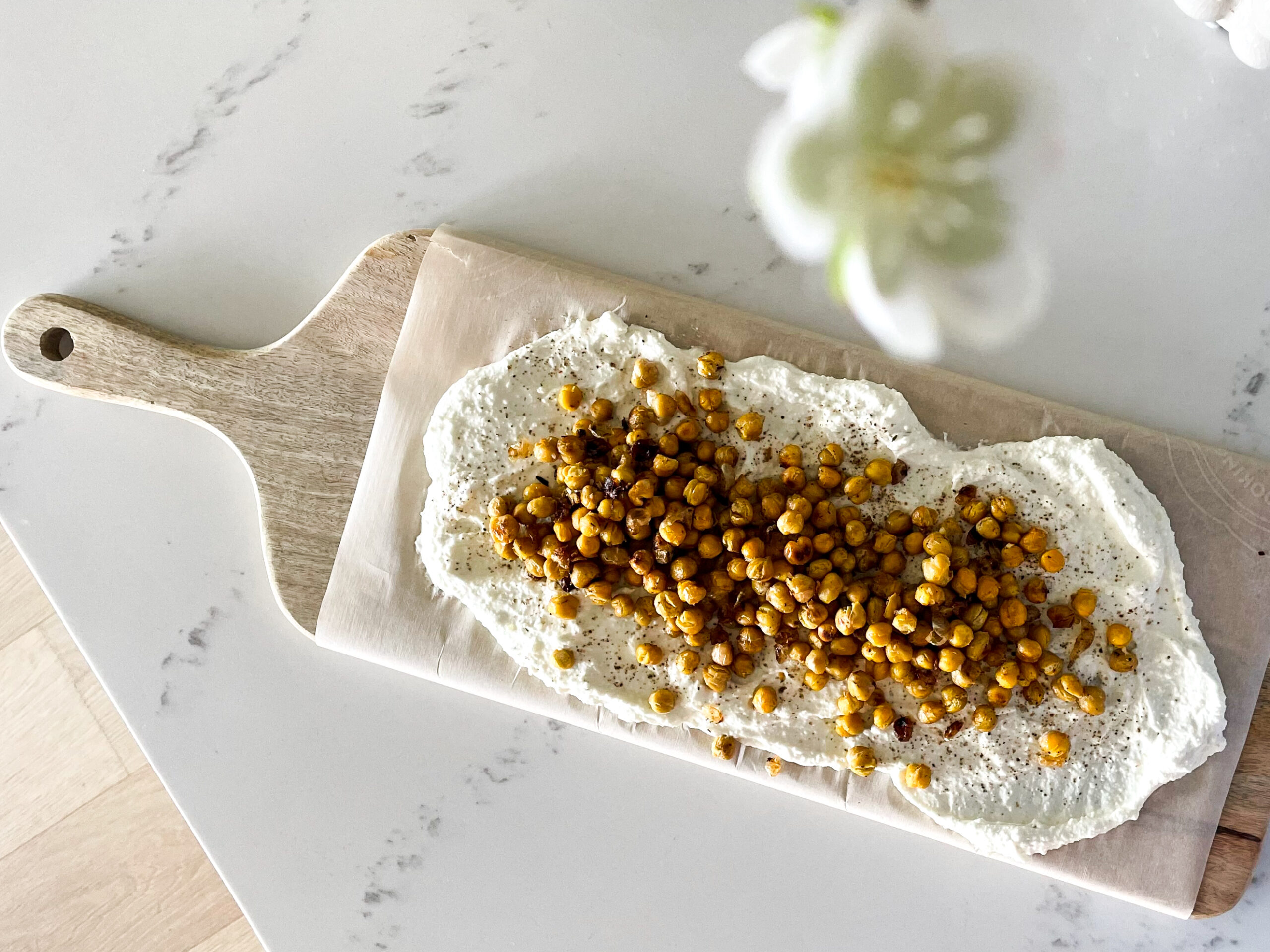 A delicious and simple honey whipped feta on a board with roasted chickpeas overtop