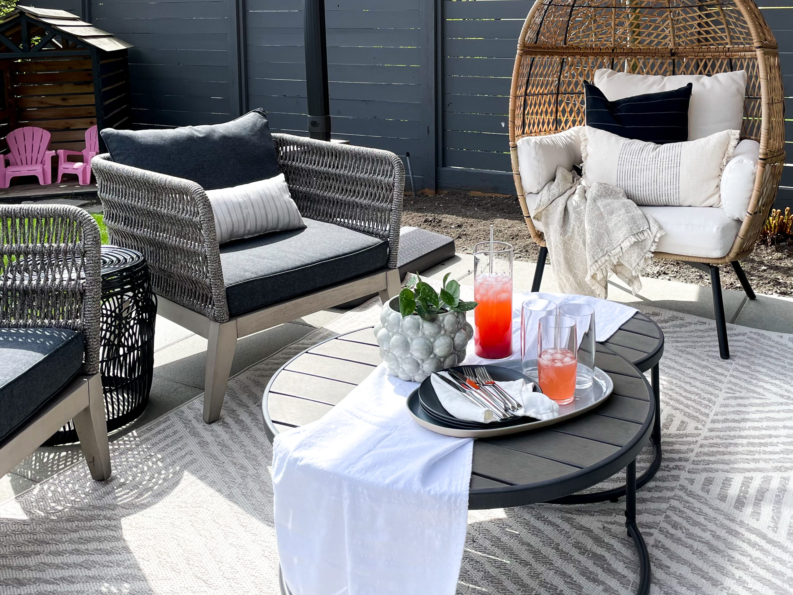 Summer Must-Have's include cozy pillows like pictured on a patio chair as well as a blanket for when the sun goes down.
