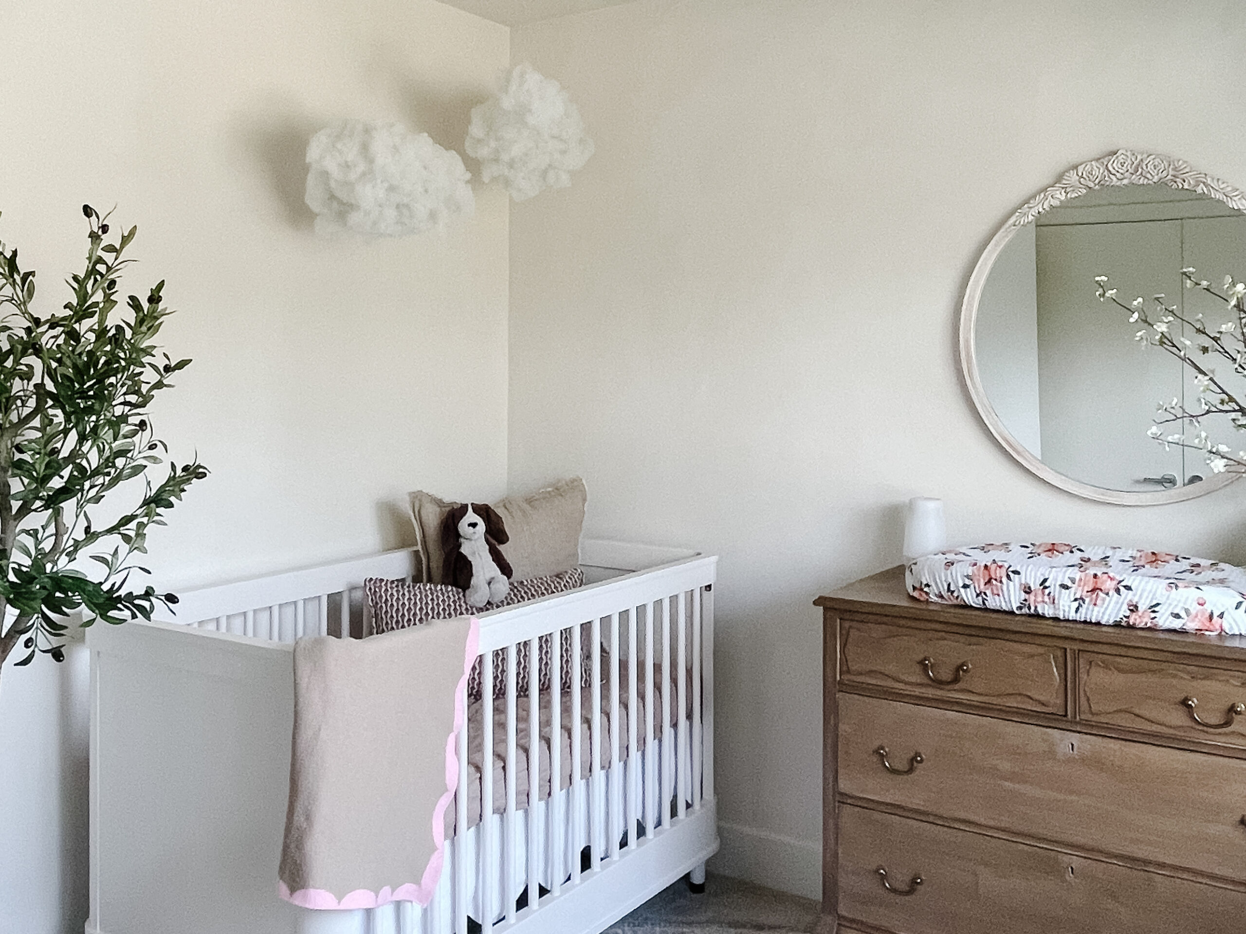 Calming nursery reveal with lime washed walls, an antiqued upcyled dresser, faux clouds, olive tree, and distressed mirror. All in small spaces